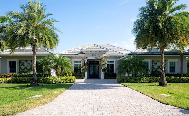 view of front of house with french doors, a front yard, decorative driveway, and stucco siding