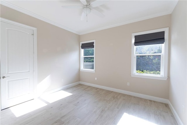empty room featuring light wood-type flooring, a healthy amount of sunlight, crown molding, and baseboards