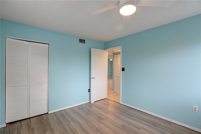 unfurnished bedroom featuring light hardwood / wood-style floors, ceiling fan, and a closet