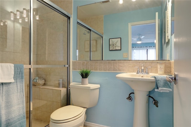 bathroom with a shower with door, toilet, and decorative backsplash