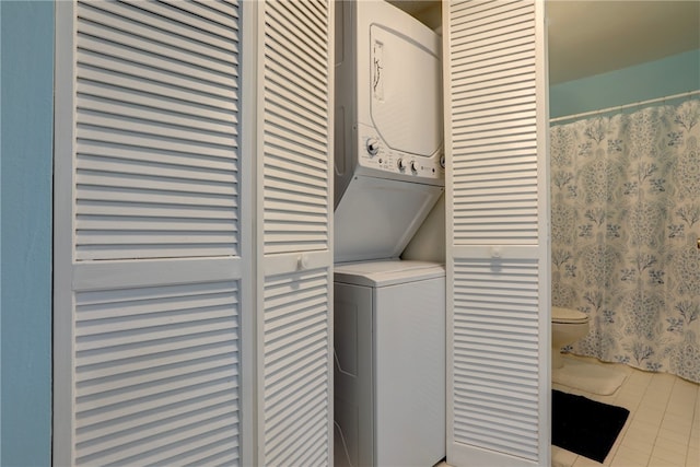 laundry area featuring stacked washer / dryer and light tile patterned flooring