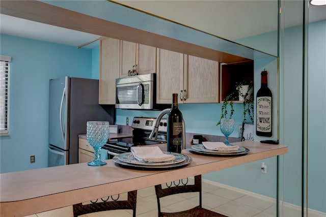 kitchen featuring light brown cabinets, appliances with stainless steel finishes, and light tile patterned floors