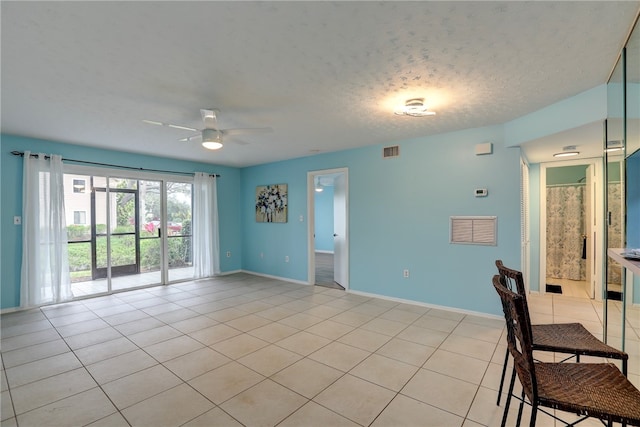 empty room with a textured ceiling, light tile patterned floors, and ceiling fan