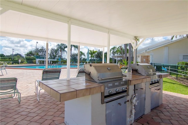 view of patio / terrace featuring a fenced in pool, exterior kitchen, and grilling area