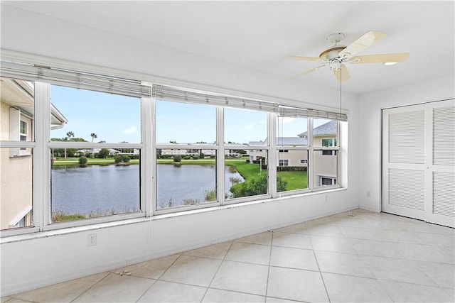 unfurnished sunroom featuring ceiling fan and a water view