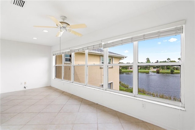 unfurnished sunroom with ceiling fan, a water view, and a healthy amount of sunlight