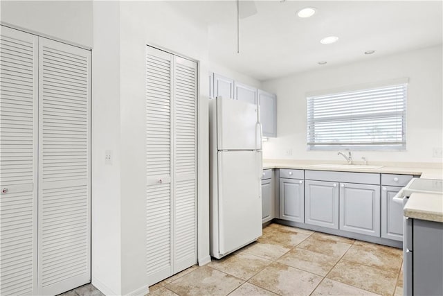 kitchen featuring gray cabinetry, sink, light tile patterned flooring, and white refrigerator