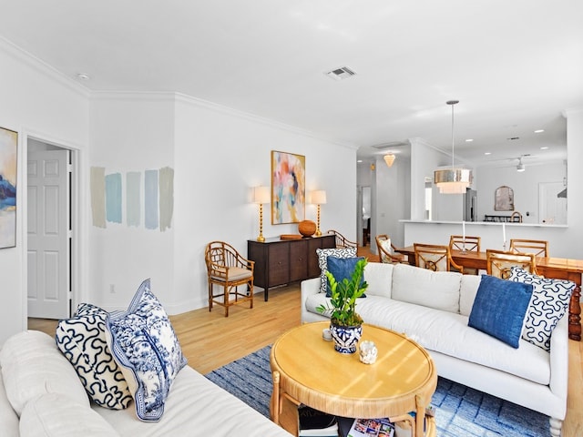 living room featuring hardwood / wood-style flooring, ceiling fan, and crown molding