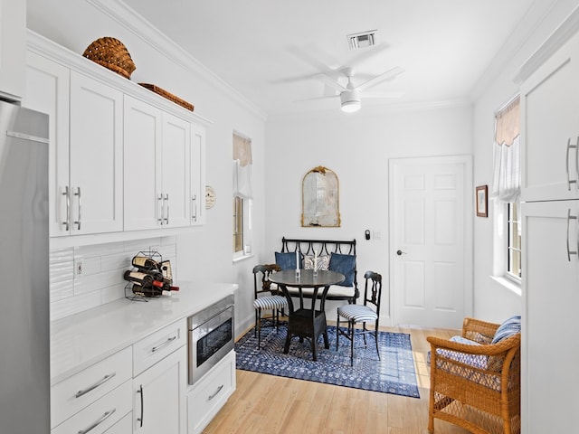 kitchen with fridge, white cabinets, stainless steel microwave, and crown molding