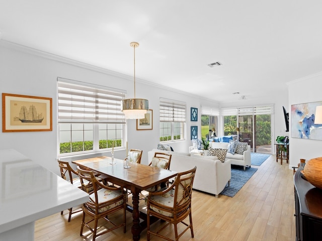 dining room with ornamental molding and light hardwood / wood-style flooring