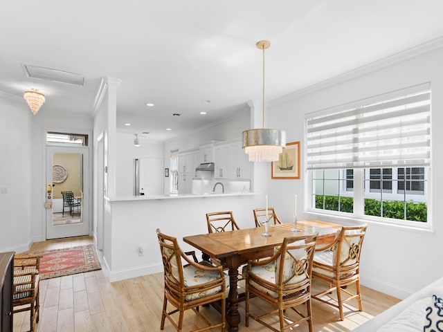 dining room with light hardwood / wood-style floors, crown molding, and sink