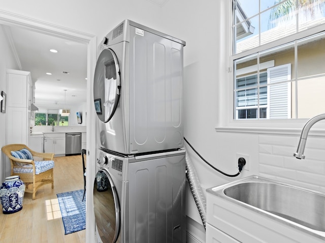 laundry room featuring sink, light hardwood / wood-style flooring, and stacked washer / drying machine