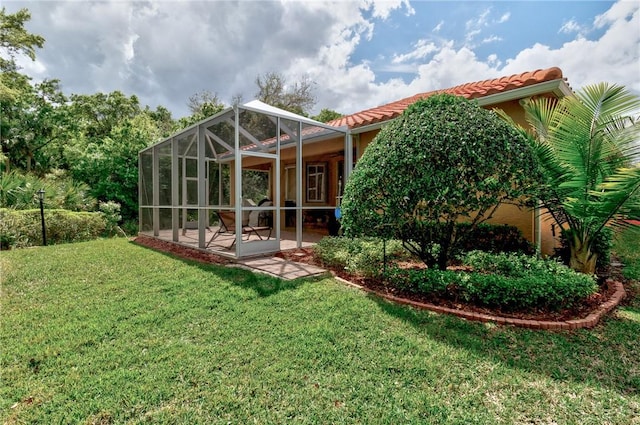 rear view of property with a lanai, a lawn, a tiled roof, and a patio