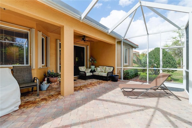 view of patio / terrace featuring glass enclosure, ceiling fan, and an outdoor living space