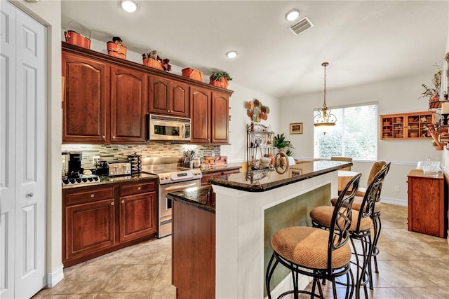 kitchen featuring visible vents, decorative backsplash, a kitchen breakfast bar, a center island, and stainless steel appliances