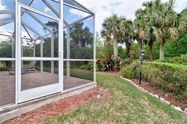 view of yard featuring glass enclosure and a patio