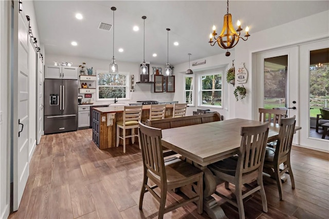 dining room with sink, french doors, a barn door, a notable chandelier, and hardwood / wood-style flooring