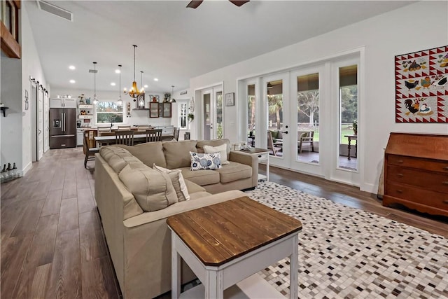 living room featuring french doors, dark wood-type flooring, and ceiling fan with notable chandelier