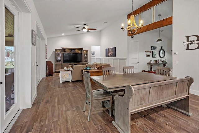 dining room featuring ceiling fan with notable chandelier, dark wood-type flooring, and lofted ceiling