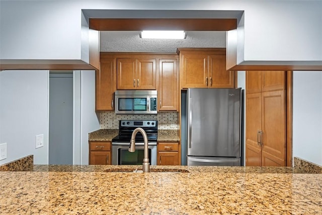 kitchen with light stone counters, sink, and stainless steel appliances