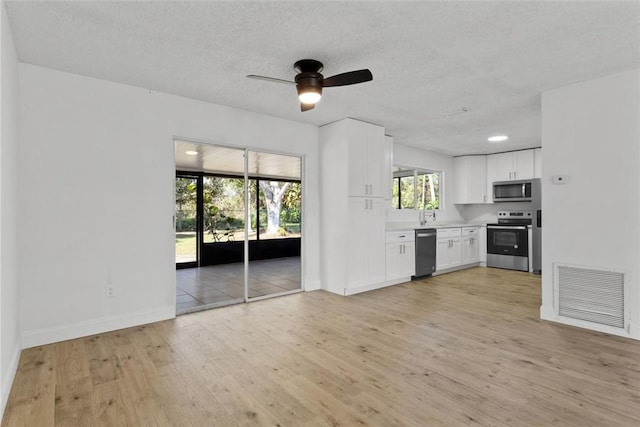 kitchen featuring ceiling fan, a textured ceiling, light hardwood / wood-style floors, white cabinetry, and stainless steel appliances