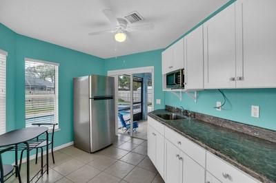 kitchen featuring appliances with stainless steel finishes, white cabinetry, sink, dark stone counters, and ceiling fan