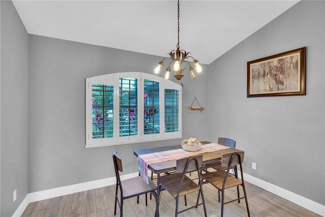 dining area featuring wood-type flooring, a chandelier, and vaulted ceiling