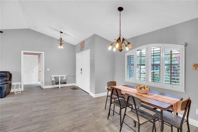 dining space featuring hardwood / wood-style flooring, vaulted ceiling, and a notable chandelier