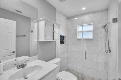 bathroom featuring an enclosed shower, vanity, and toilet