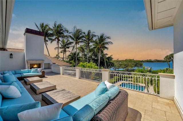 707 Grove Pl, Vero Beach, FL 32963 - patio terrace at dusk with an outdoor living space with a fireplace, a water view, and a patio area