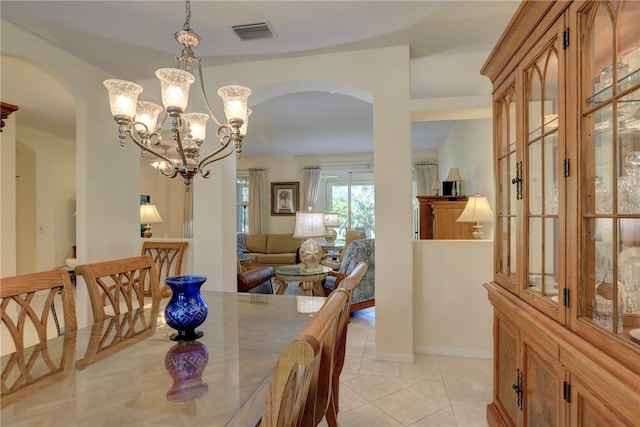 dining space featuring arched walkways, visible vents, an inviting chandelier, and light tile patterned floors