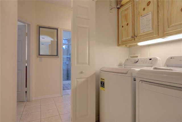 laundry room featuring light tile patterned floors, cabinet space, and washing machine and dryer