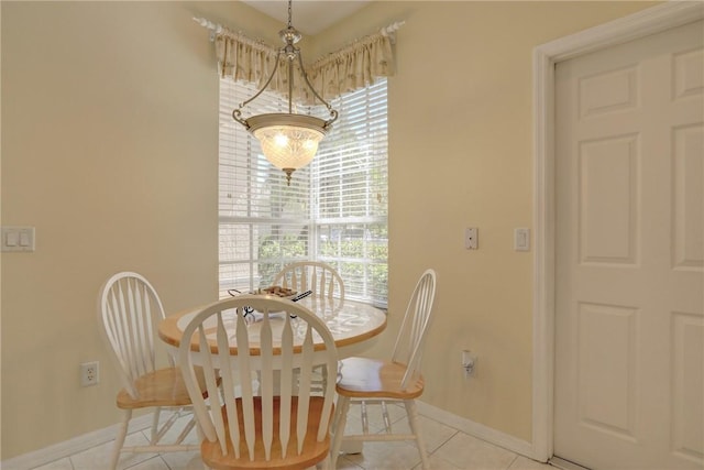 tiled dining room featuring a notable chandelier and baseboards