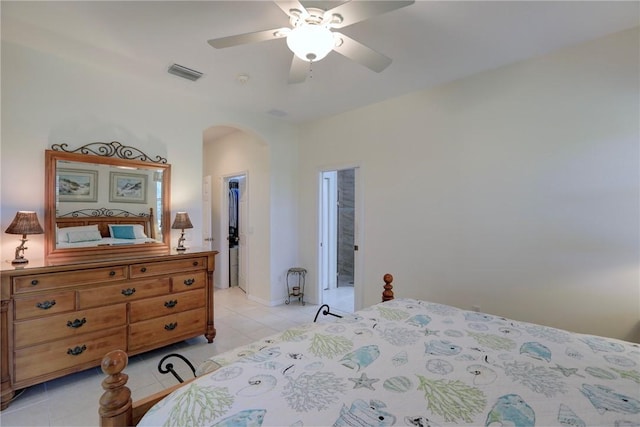 bedroom with visible vents, a walk in closet, light tile patterned floors, arched walkways, and a ceiling fan