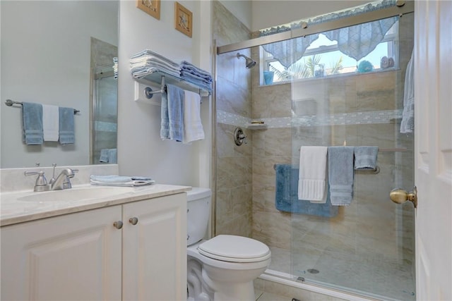 bathroom with tile patterned flooring, a shower stall, toilet, and vanity