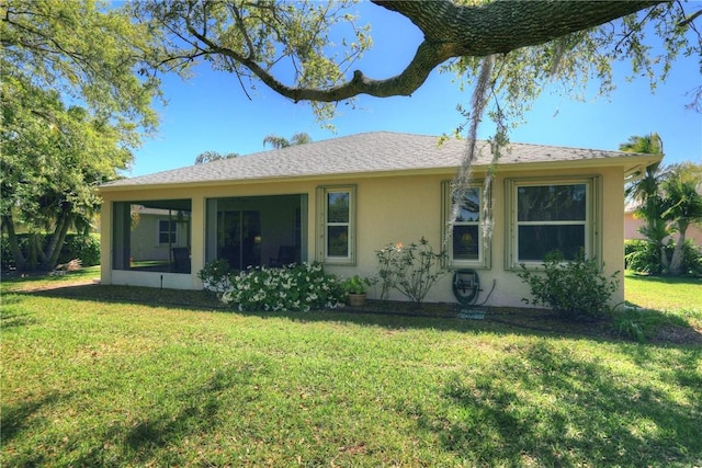 back of house with stucco siding, a lawn, and a sunroom