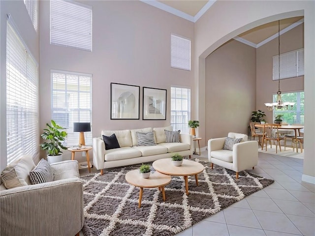 living room featuring tile patterned flooring, crown molding, a high ceiling, and an inviting chandelier