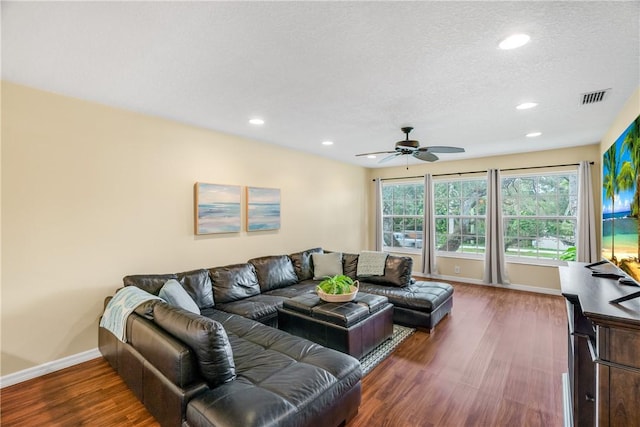 living room featuring ceiling fan, dark hardwood / wood-style flooring, and a textured ceiling