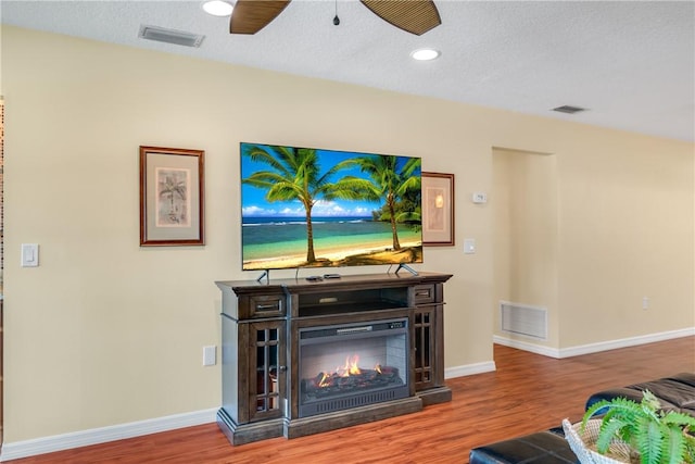 living room with hardwood / wood-style flooring, a textured ceiling, and ceiling fan