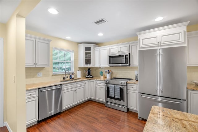 kitchen featuring sink, light stone counters, appliances with stainless steel finishes, dark hardwood / wood-style floors, and white cabinets