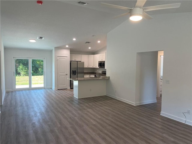 kitchen with appliances with stainless steel finishes, white cabinetry, lofted ceiling, dark hardwood / wood-style flooring, and kitchen peninsula