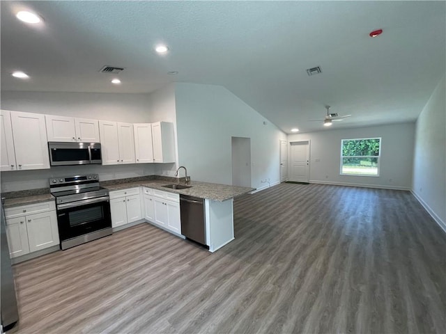 kitchen with sink, vaulted ceiling, kitchen peninsula, stainless steel appliances, and white cabinets