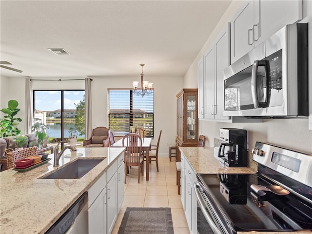 kitchen featuring pendant lighting, white cabinets, a water view, sink, and stainless steel appliances