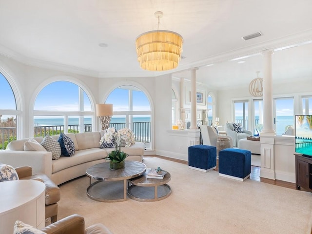 living room with ornate columns, crown molding, a water view, and a notable chandelier