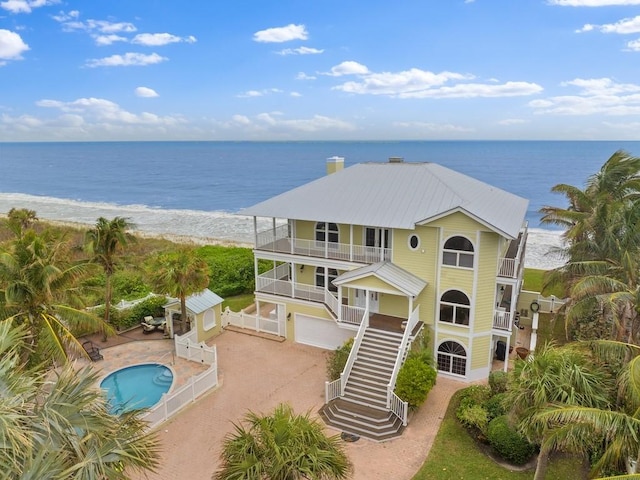 exterior space featuring a beach view, a water view, and a patio area