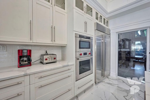 kitchen featuring light stone counters, white cabinets, marble finish floor, appliances with stainless steel finishes, and tasteful backsplash