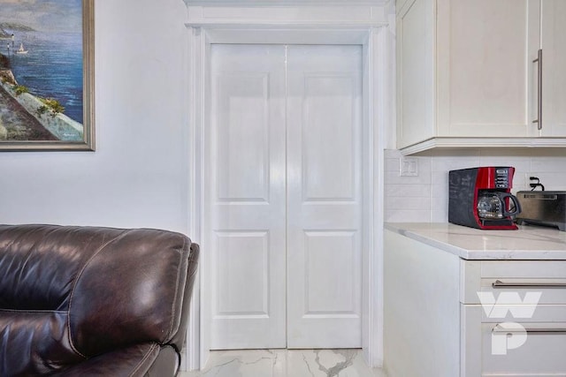 interior space with white cabinetry, light stone counters, and decorative backsplash