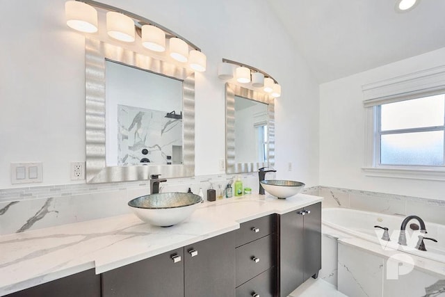 bathroom featuring lofted ceiling, vanity, and a tub