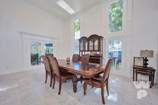 dining area with marble finish floor, baseboards, and high vaulted ceiling