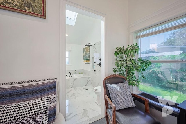 bathroom featuring marble finish floor, a skylight, a tub with marble appearance, and toilet